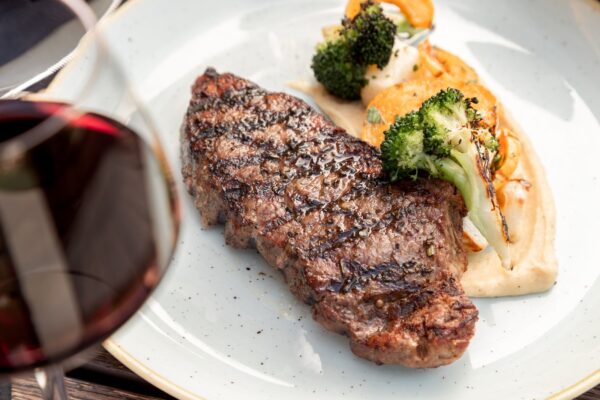 a white plate topped with a New York Strip Steak and roasted vegetables