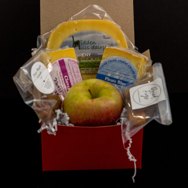 a cheese box with three wedges of cheese, an apple, dried figs and maple candies