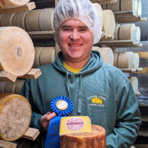 Anthony Rice holding a wheel and wedge of Winemakers Select, blue ribbon winner at the 2025 Farm Show