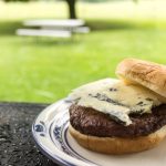 a beef patty topped with a slice of blue cheese