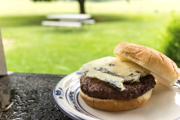 a beef patty topped with a slice of blue cheese